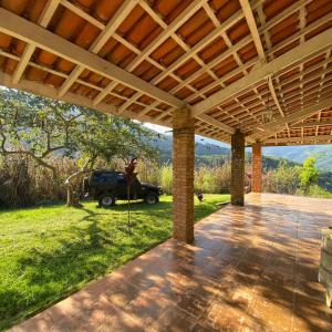an outdoor patio with a roof with a jeep in the background at Chácara Palma in Ubatuba
