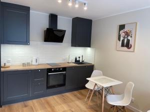 a kitchen with blue cabinets and a table and chairs at Apartament Radiowa Premium in Olsztyn