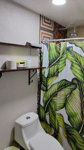 a bathroom with a toilet and a tropical shower curtain at Casas centro Loreto in Loreto