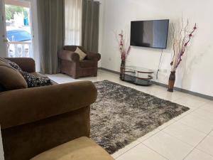 uma sala de estar com um sofá e uma televisão em Weekendz- Cozy 2BRD Suite em Port Antonio