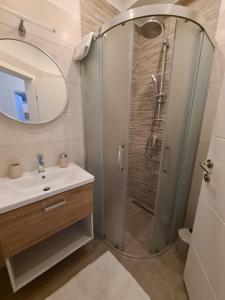 a bathroom with a shower with a sink and a mirror at Apartman Zrno in Vodice +40 photos