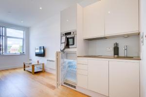 a kitchen with white cabinets and a wooden floor at The Landmark, Lutons best location in Luton