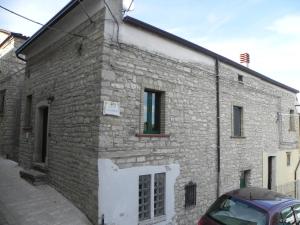 a brick building with a white door and a car parked outside at Casa Vacanze Faeto in Faeto