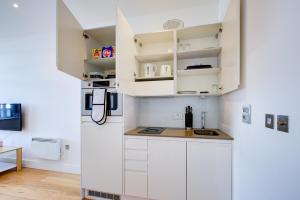 a kitchen with white cabinets and a refrigerator at The Landmark, Lutons best location in Luton +16 photos
