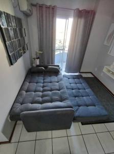 un gran sofá azul en una habitación con ventana en 2 Apto na principal de canasvieiras en Florianópolis