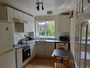 een keuken met witte kasten en een tafel en een raam bij Spacious Room in Leafy, Quiet N4 in Londen