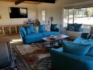 a living room with blue couches and a flat screen tv at Sandcreek Cottage / Fabulous Views on Five Acres in Torrey