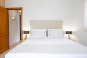 Adria Luxury Apartments في نيدري: غرفة نوم بسرير ابيض كبير ومصباحين