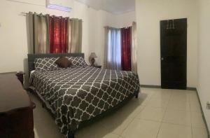 a bedroom with a bed with a black and white comforter at Weekendz- Cozy 2BRD Suite in Port Antonio
