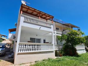 a white house with a balcony and a tree at Apartman Zrno in Vodice