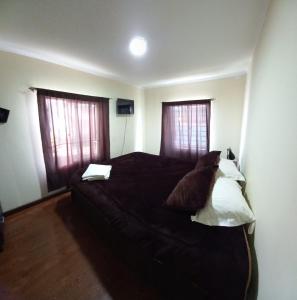 1 dormitorio con 1 cama grande y 2 ventanas en Casa Cely, en Iquique