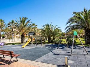 un parque con parque infantil, banco y palmeras en Estrella de Mar en Dénia
