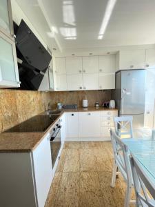uma cozinha com armários brancos e uma mesa com cadeiras em Marble Apartament em Zamość