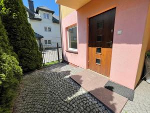 a pink house with a brown door on a brick sidewalk at Marble Apartament in Zamość