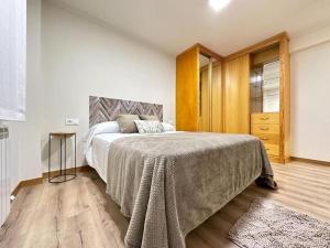 ein Schlafzimmer mit einem großen Bett und Holzboden in der Unterkunft Amplio apartamento con terraza en Bouzas, cerca de la playa. in Vigo