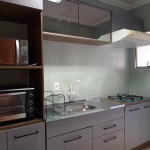 a kitchen with a sink and a microwave at Espaço aconchegante em Criciúma in Criciúma