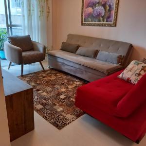 uma sala de estar com um sofá e um repousa-pés vermelhos em Espaço aconchegante em Criciúma em Criciúma