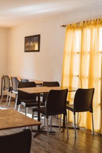 a row of tables and chairs in a room with yellow curtains at Hostel House 64Bigüa in El Calafate