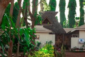 een wit huis met een zwart dak en bomen bij The Secret Garden Hotel Moshi in Moshi