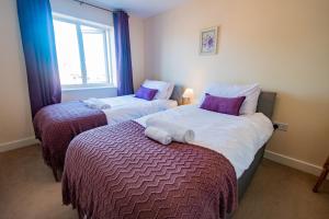two twin beds in a room with a window at Serene Sands in Felixstowe