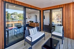 a balcony with two chairs and a living room at Brand New with Ocean Views in Wellington