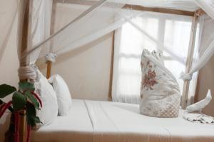 een wit bed met witte kussens en een raam bij The Secret Garden Hotel Moshi in Moshi