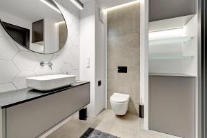 a white bathroom with a sink and a mirror at Sleepy3city Apartments Batorego 9 in Gdynia