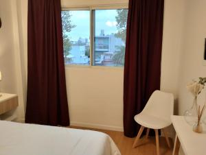 1 dormitorio con ventana, 1 cama blanca y 1 silla en Humboldt 2 en Buenos Aires