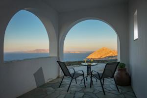 a patio with two chairs and a table with a view of the ocean at Aegean Balcony in Ano Meria