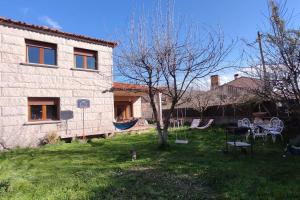 una casa con un patio con una hamaca y un árbol en La casa del fresno, en Pinilla del Valle