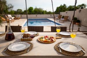 Seven Olives Guest House with heated pool near Krka waterfalls في Planjane: طاولة مع أطباق من الطعام وكؤوس من النبيذ