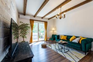 Seven Olives Guest House with heated pool near Krka waterfalls في Planjane: غرفة معيشة مع أريكة خضراء ومدفأة