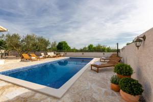 Seven Olives Guest House with heated pool near Krka waterfalls في Planjane: مسبح في ساحة فيها كراسي وفناء