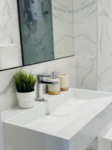 a white bathroom with a sink and a mirror at Canopy Aldgate in London