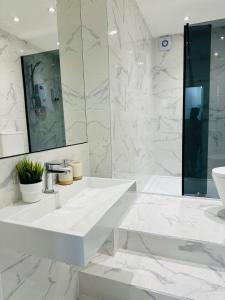 a white bathroom with a sink and a mirror at Canopy Aldgate in London