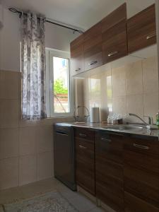 eine Küche mit Holzschränken, einem Waschbecken und einem Fenster in der Unterkunft Popi in Budva