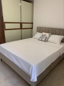 ein Bett mit weißer Bettwäsche und Kissen in einem Schlafzimmer in der Unterkunft Popi in Budva