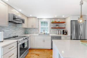 una cocina con armarios blancos y electrodomésticos de acero inoxidable en Queen Anne, en Chatham