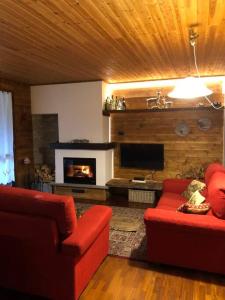 ein Wohnzimmer mit 2 roten Stühlen und einem Kamin in der Unterkunft Appartamento ampio giardino adiacente piste sci in La Thuile
