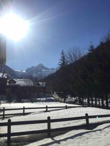 Une clôture dans la neige avec le soleil derrière elle dans l'établissement Appartamento ampio giardino adiacente piste sci 4/6 posti letto, à La Thuile