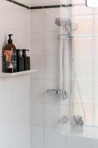 a shower in a bathroom with a white tiled wall at City Edge Home From Home in Keswick