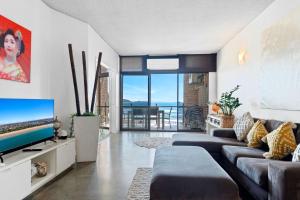 un salon avec un canapé et une télévision dans l'établissement 2 bedrooms 2 baths with balcony and ocean views, across from ocean, à Alexandra Headland