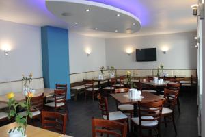 a dining room with tables and chairs and a tv at City Lounge Hotel in Düsseldorf