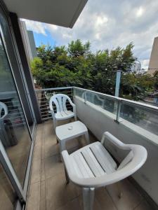 a balcony with two white chairs and a table at Hermoso departamento en Flores! in Buenos Aires