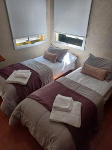 duas camas num quarto de hotel com duas janelas em Sofia del Bosque em Mar del Plata