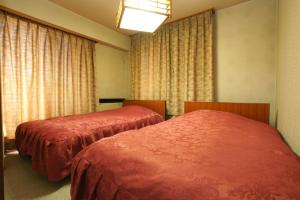 two beds in a room with windows and curtains at Imakuni Ryokan in Takachiho +18 photos