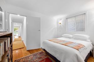 a white bedroom with a bed and a window at Waters Edge in Frankston