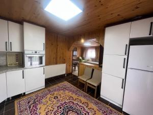 una cocina con armarios blancos y una alfombra en el suelo en Cay Suite, en Uzungöl