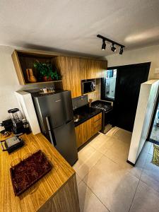 eine Küche mit einem schwarzen Kühlschrank und Holzschränken in der Unterkunft Apartamento Vila do Lago in Mata de Sao Joao