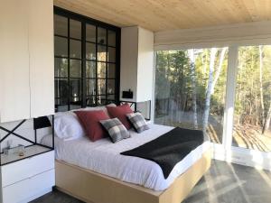 um quarto com uma cama e uma grande janela em Charlevoix expérience thermale en pleine nature - Suites Nature Charlevoix - Suite #2 em Les Éboulements